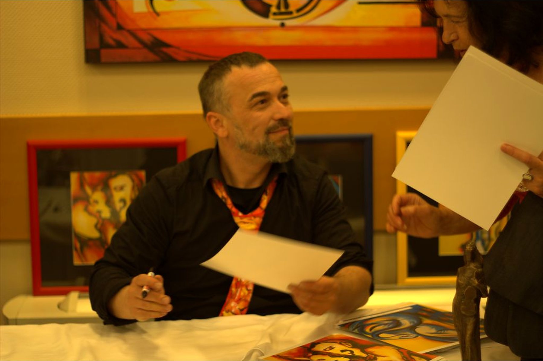 Joe Muczka jr. signiert an der Autogrammstunde, Werke im Hintergrund